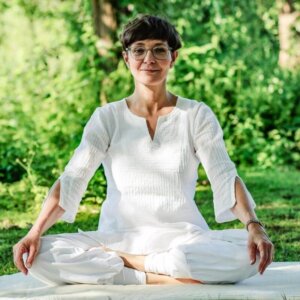 Simone sitzt in Yoga-Pose und freut sich auf die Auszeit-Wochenenden.